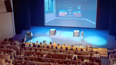 El mago con una ni&ntilde;a en el escenario interact&uacute;a con una espectadora