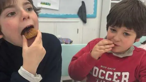 Dos alumnos, hermanos, comen las aceitadas elaboradas por ellos mismos