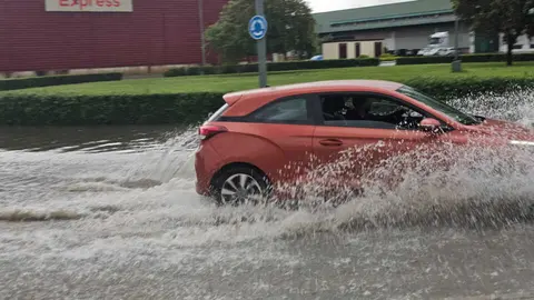 Coche circula por una calle anegada