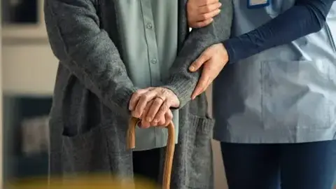 Una cuidadora acompa&ntilde;a a un residente
