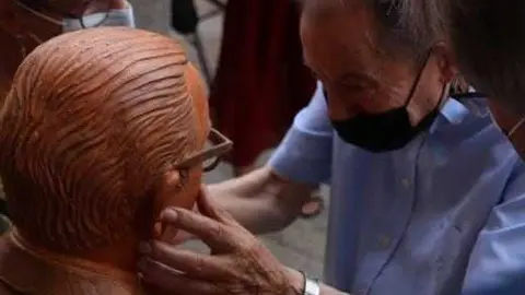 Herminio Ramos frente a su escultura