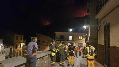 Personal contra incendios observan las llamas desde Casillas, el domingo por la noche.