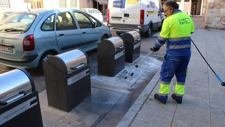 Un operario limpia pintadas cerca de los contenedores de basura