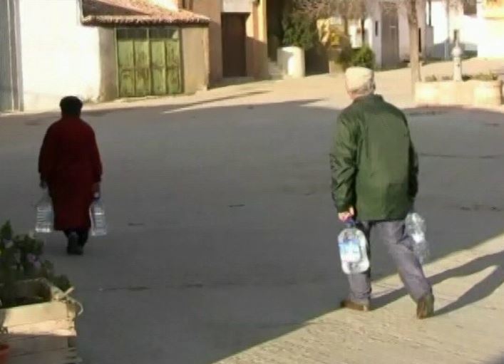 Vecinos de un pueblo caminan con garrafas de agua.