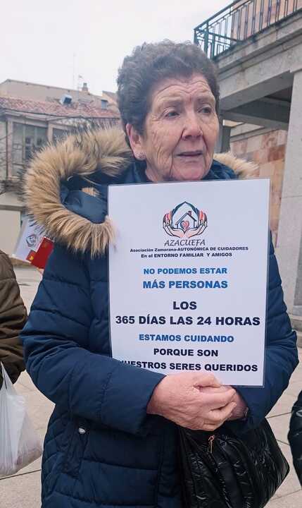 Una cuidadora con un cartel de protesta