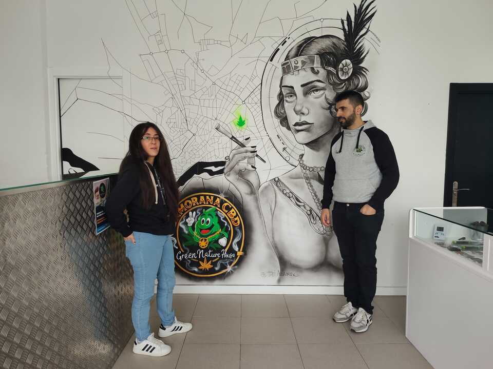 Pedro y Fany junto al mural que luce en la tienda de la Plaza de Cristo Rey