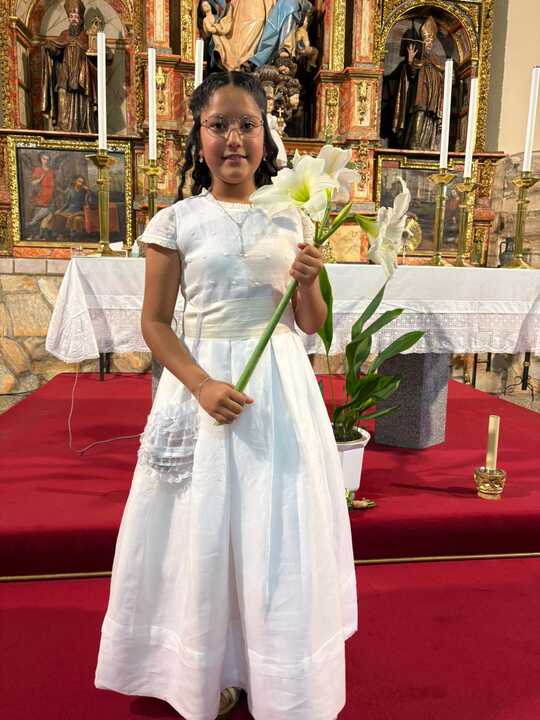 Valery vestida de comunión con una flor